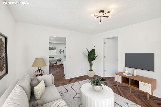 living room featuring a textured ceiling, parquet flooring, and a chandelier