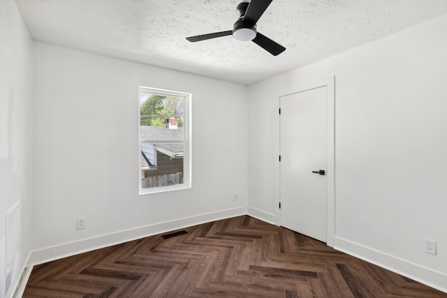 empty room featuring ceiling fan, a textured ceiling, and dark parquet flooring