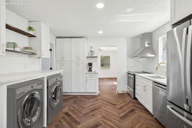 kitchen with stainless steel appliances, white cabinetry, and washer and dryer