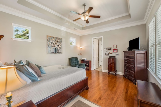 bedroom with a tray ceiling, ornamental molding, ceiling fan, and hardwood / wood-style flooring