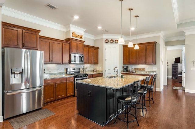 kitchen featuring a kitchen breakfast bar, stainless steel appliances, a center island with sink, dark hardwood / wood-style flooring, and light stone countertops