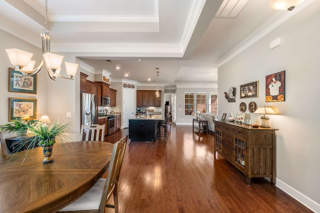 dining room featuring ornamental molding, dark hardwood / wood-style floors, a tray ceiling, and a chandelier