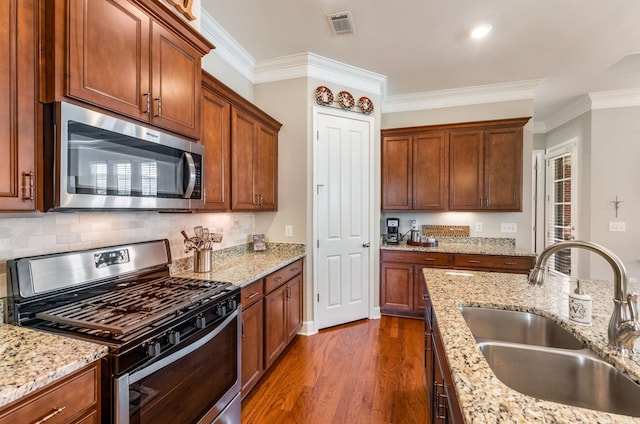 kitchen with ornamental molding, appliances with stainless steel finishes, dark wood-type flooring, and sink