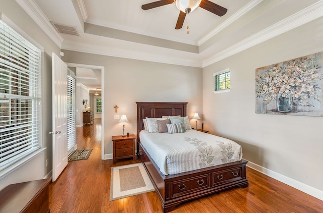 bedroom featuring a raised ceiling, ornamental molding, hardwood / wood-style floors, and ceiling fan