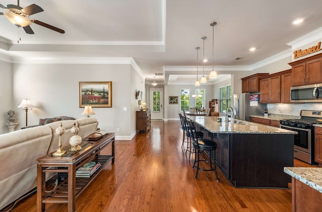 kitchen with appliances with stainless steel finishes, a kitchen bar, ceiling fan, decorative light fixtures, and dark hardwood / wood-style floors