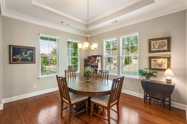 dining area featuring a chandelier, a raised ceiling, dark wood-type flooring, and crown molding