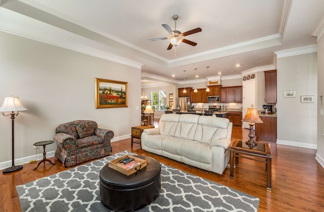 living room with crown molding, a tray ceiling, dark hardwood / wood-style flooring, and ceiling fan