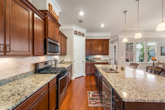 kitchen with dark hardwood / wood-style floors, sink, a kitchen breakfast bar, a center island with sink, and appliances with stainless steel finishes