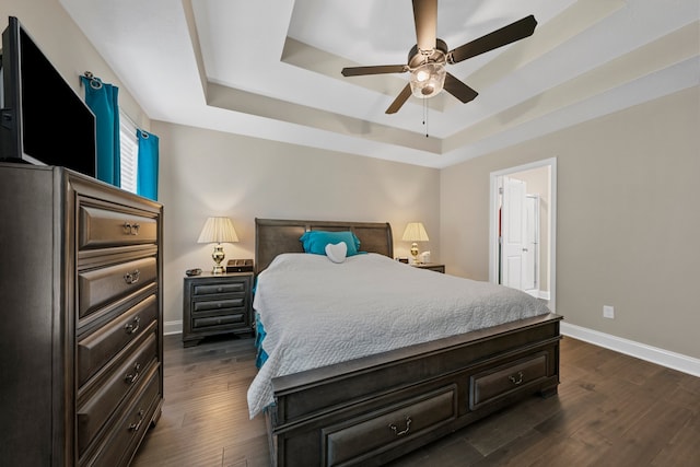 bedroom featuring a tray ceiling, dark hardwood / wood-style flooring, and ceiling fan