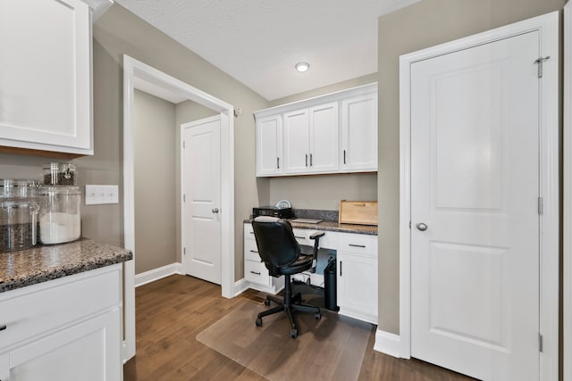 office area featuring a textured ceiling, built in desk, and dark hardwood / wood-style flooring