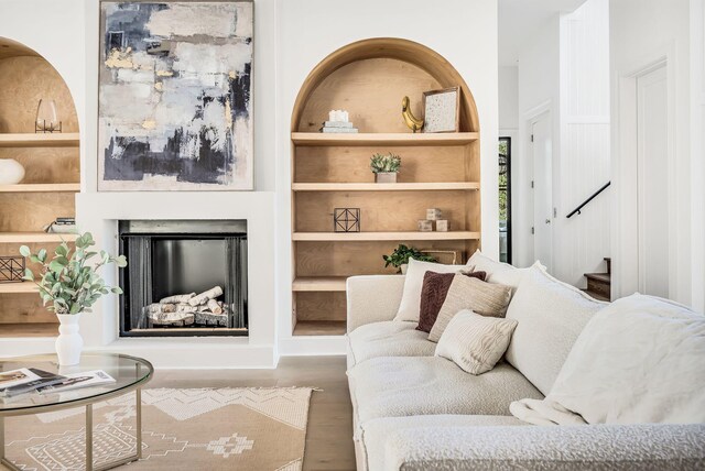 living room with built in shelves and hardwood / wood-style floors