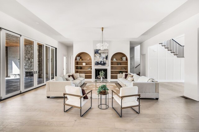 living room with a notable chandelier, built in features, and light hardwood / wood-style floors