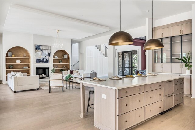 kitchen with hanging light fixtures, a kitchen island, light brown cabinets, and a kitchen breakfast bar