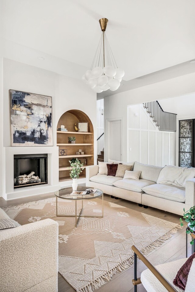 living room with built in shelves, hardwood / wood-style floors, and a chandelier