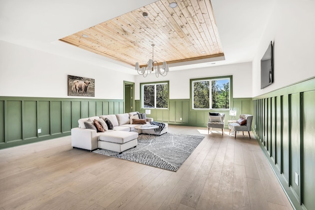 living area with wood ceiling, a tray ceiling, a notable chandelier, and light wood-type flooring