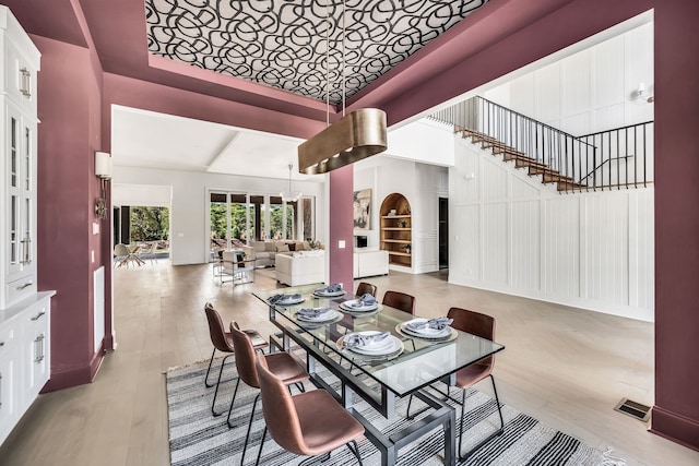 dining room with light wood-type flooring and a towering ceiling