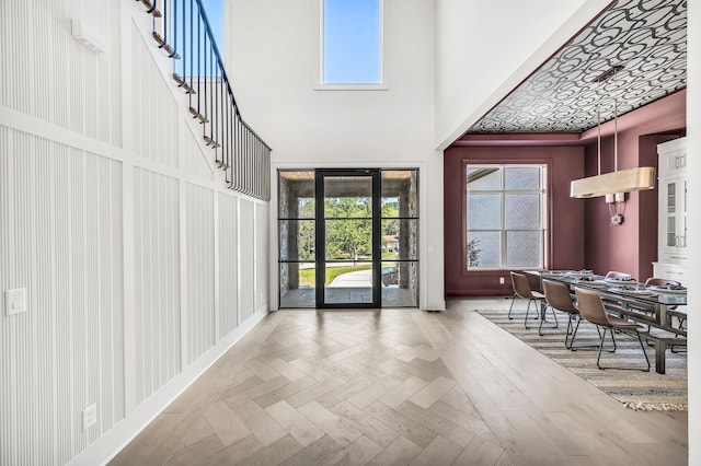 foyer entrance with a towering ceiling and parquet floors