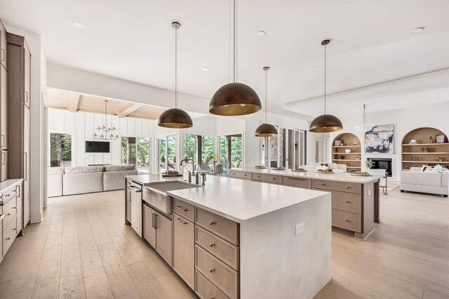 kitchen featuring a large island, hanging light fixtures, sink, and light wood-type flooring