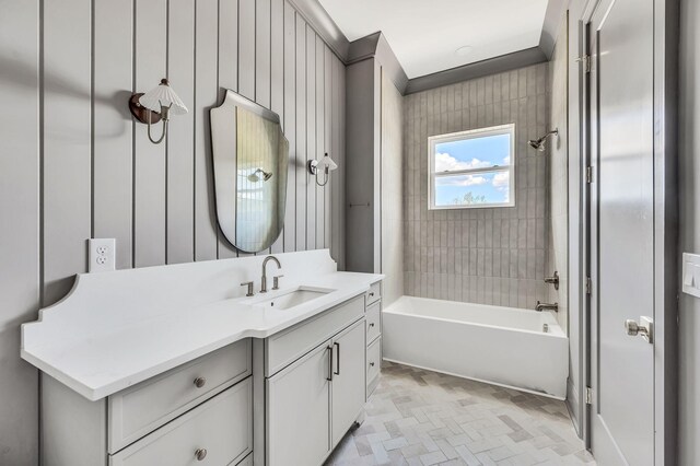 bathroom with vanity, wooden walls, and tiled shower / bath combo