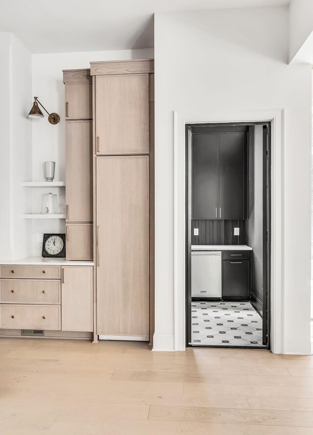 kitchen featuring stainless steel dishwasher, light brown cabinetry, and light hardwood / wood-style flooring