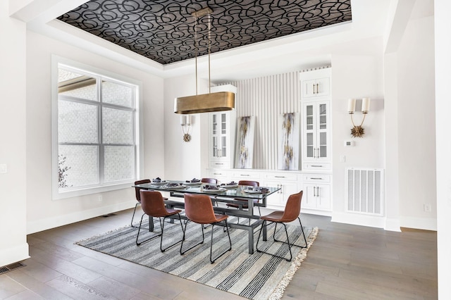 dining space with dark hardwood / wood-style floors and a tray ceiling