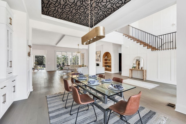 dining room featuring an inviting chandelier, hardwood / wood-style flooring, and a high ceiling