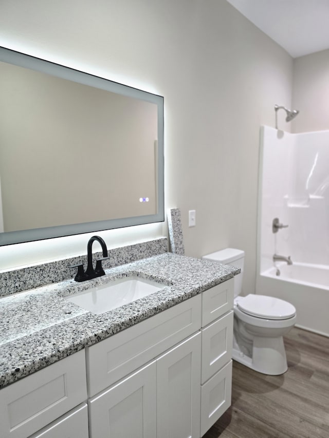 full bathroom featuring wood-type flooring, vanity, toilet, and washtub / shower combination