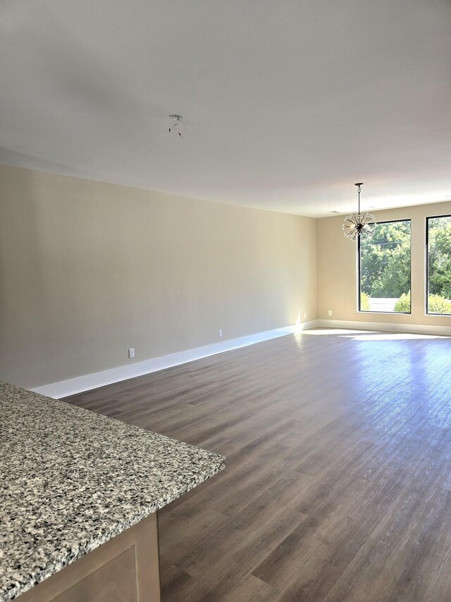 spare room featuring an inviting chandelier and dark hardwood / wood-style flooring