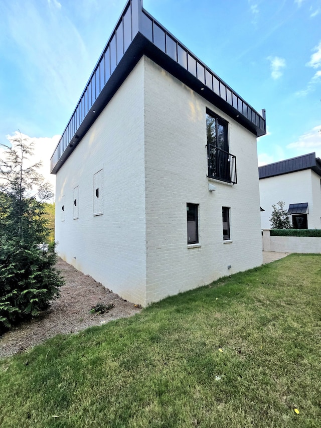 view of side of property featuring a lawn and a balcony