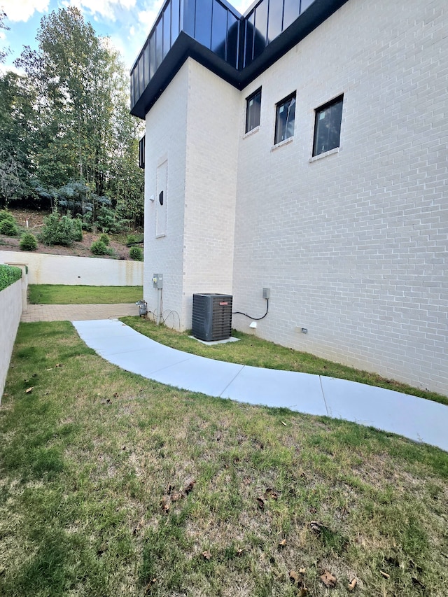 view of property exterior featuring a lawn, a balcony, and central AC unit