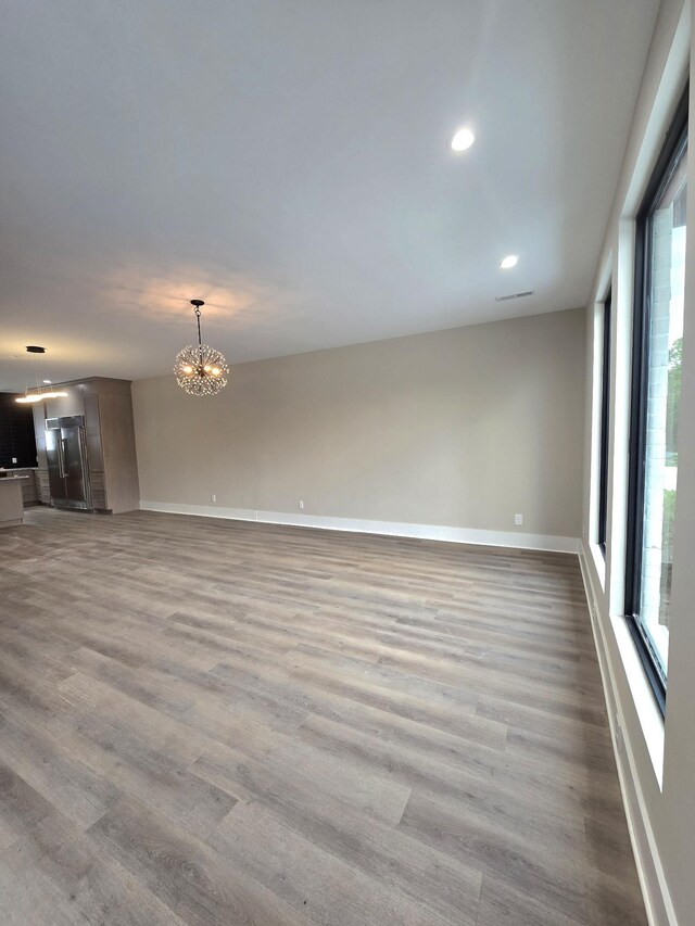 unfurnished living room featuring a notable chandelier, light hardwood / wood-style floors, and plenty of natural light