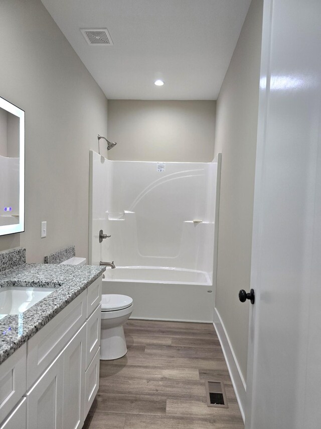 full bathroom with shower / bathing tub combination, vanity, hardwood / wood-style floors, and toilet