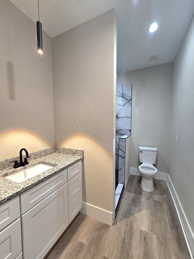 bathroom featuring walk in shower, vanity, hardwood / wood-style floors, and toilet