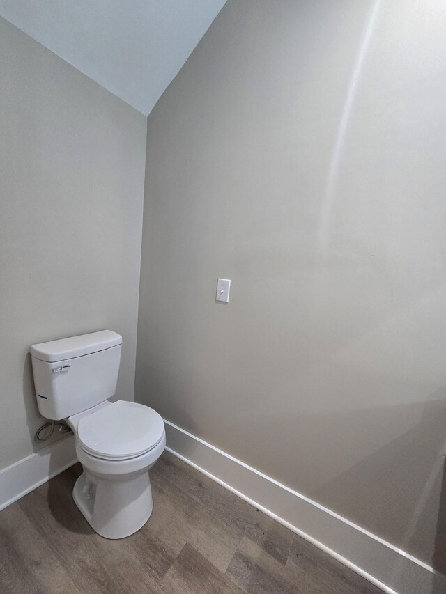 bathroom with lofted ceiling, toilet, and hardwood / wood-style flooring