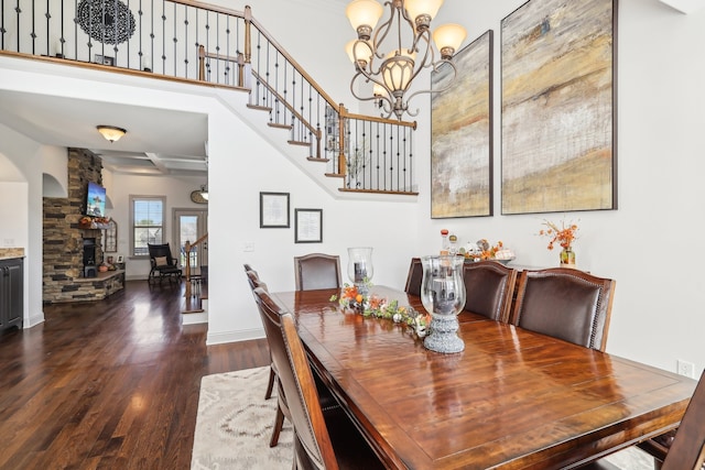 dining space featuring a stone fireplace, dark hardwood / wood-style floors, and a chandelier