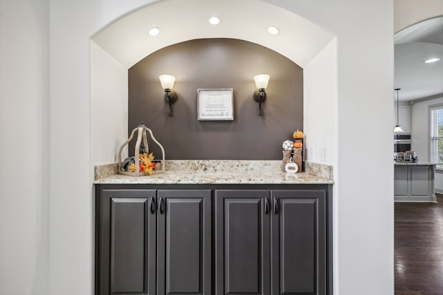 bar featuring light stone counters, oven, and dark hardwood / wood-style flooring