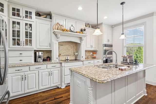 kitchen with white cabinets, decorative backsplash, a center island with sink, decorative light fixtures, and dark hardwood / wood-style flooring