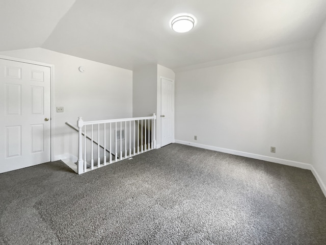 spare room featuring dark carpet and lofted ceiling