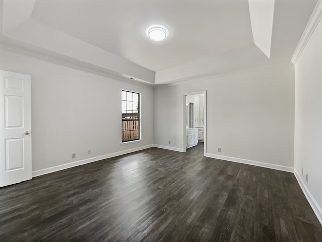 empty room featuring a raised ceiling, dark hardwood / wood-style floors, and crown molding