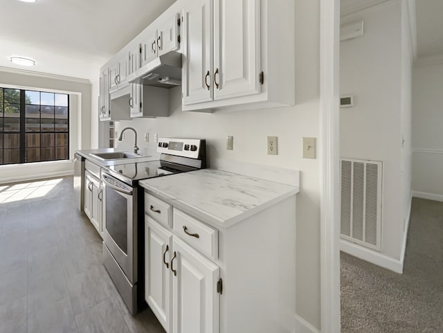 kitchen featuring white cabinets, ornamental molding, sink, appliances with stainless steel finishes, and light colored carpet