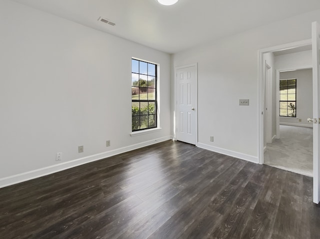 spare room with dark hardwood / wood-style flooring and plenty of natural light