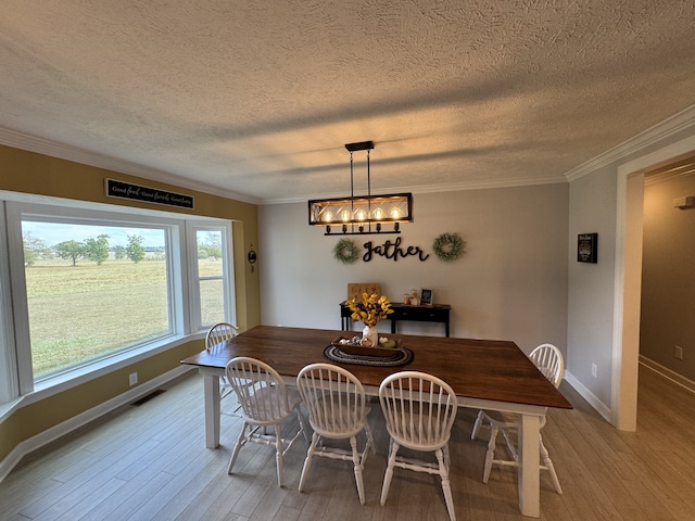 dining room featuring light hardwood / wood-style flooring, a textured ceiling, an inviting chandelier, and crown molding