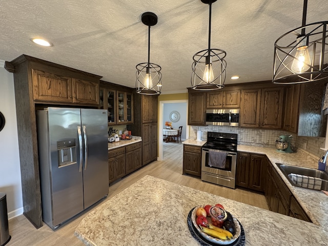 kitchen with light hardwood / wood-style floors, sink, hanging light fixtures, decorative backsplash, and appliances with stainless steel finishes