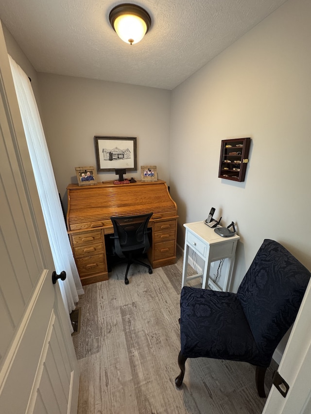 office space with a textured ceiling and light hardwood / wood-style floors