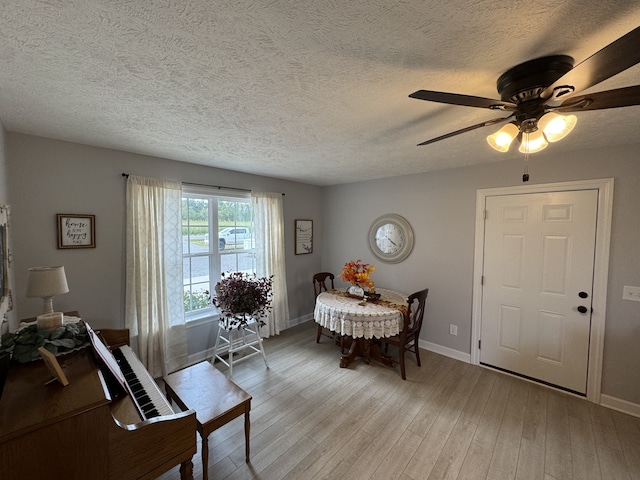 living room featuring light wood-type flooring, a textured ceiling, and ceiling fan