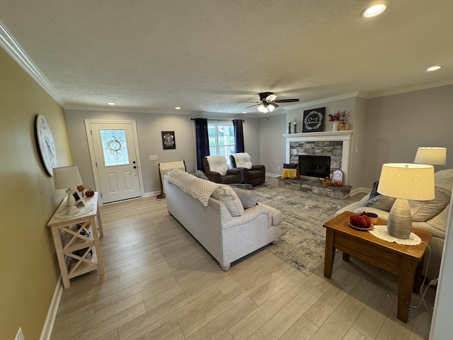 living room with crown molding, light hardwood / wood-style floors, a fireplace, and ceiling fan