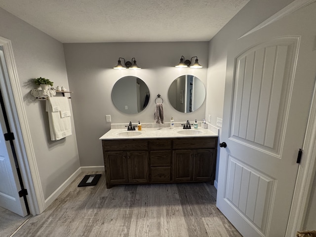 bathroom with a textured ceiling, hardwood / wood-style flooring, and vanity