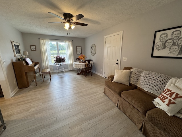 living room featuring ceiling fan, a textured ceiling, and light wood-type flooring