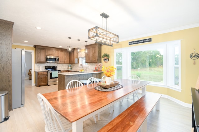 dining area with ornamental molding, light hardwood / wood-style floors, and sink