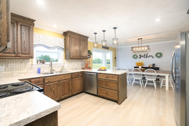 kitchen featuring appliances with stainless steel finishes, a healthy amount of sunlight, kitchen peninsula, and sink